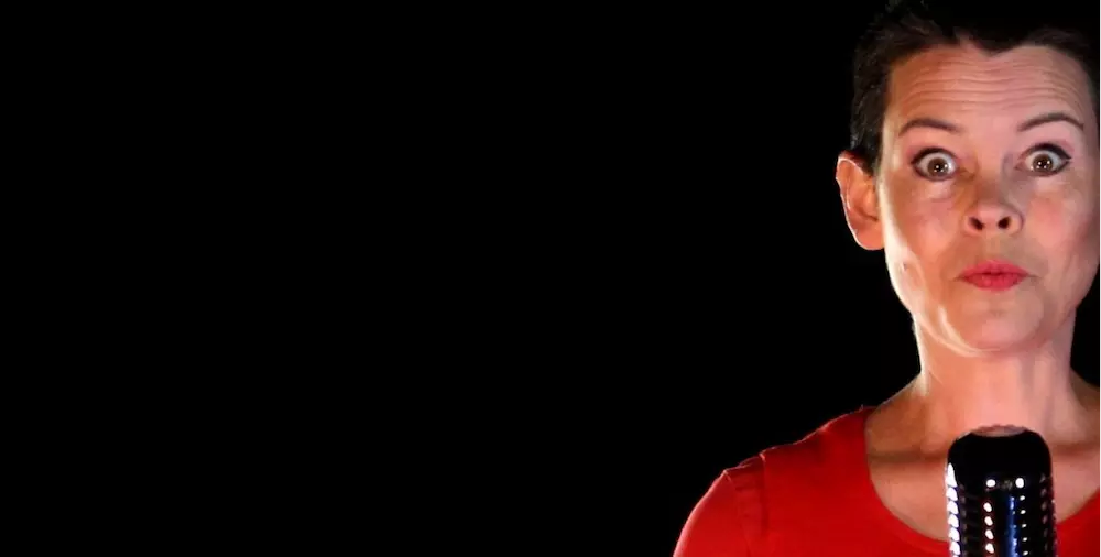 Anna wears red and speaks into a condenser microphone