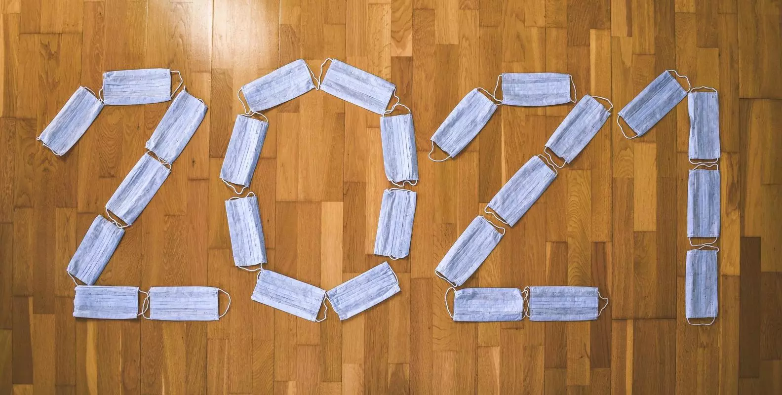 2021 spelt out with blue face masks on a wooden floor